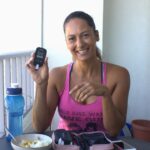 Christel holding a blood sugar meter while eating lunch on the balcony